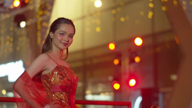 Beautiful Asian woman wearing a traditional Chinese sleeveless red dress poses while celebrating the Chinese New Year - beautiful boken in the night lights in background