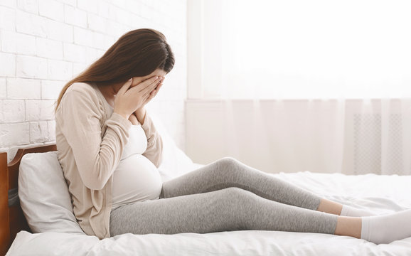 Young Pregnant Woman Feeling Sad And Crying At Home