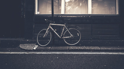  Bicycle parked in front building on the road side in a gray weather, Blue Vintage style - 320302634