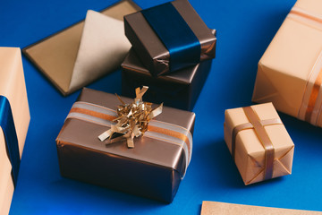 Chirsmas concept with gold boxes, envelope, wreath on blue background.