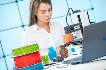 Young female designer works with a 3D printer in a design studio.