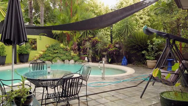 A beautiful outdoor pool surrounded by lush, green plant life in Queensland, Australia on a rainy day - Slow motion
