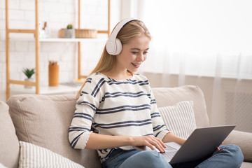 Blonde girl studying online, using wireless headphones and laptop