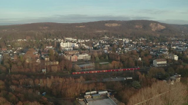 Panorama drone / aerial shot of Bonn / K&ouml;nigswinter of a red local train, the river rhine with the post tower, the kameha hotel and a ship at the afternoon, 25p