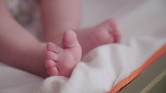 Baby wiggling feet and toes on white blanket, Close Up Focus on Foreground