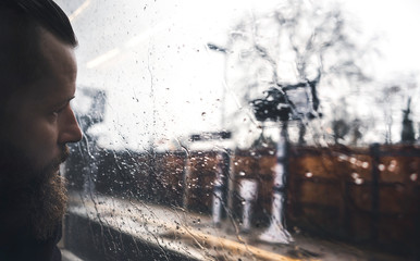 Man looking outside through the train window in a gray rainy day, Slow Travel in London - 320304826