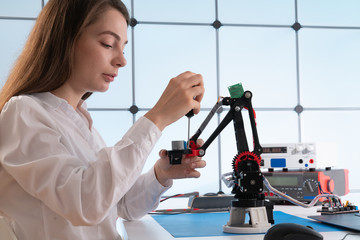 A young woman writes an algorithm for the robot arm. Science Research Laboratory for Robotic Arm...