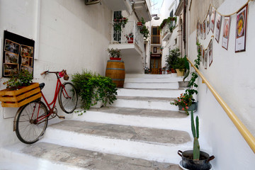 Fototapeta na wymiar Street of Ostuni town with staircase full of blooming flowers, Apulia region, Italy, Adriatic Sea