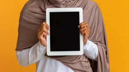 Digital tablet with black screen in hands of unrecognizable muslim woman