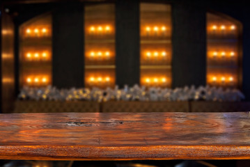 Wooden board on a background of bottles with alcohol. Old bar counter as layout for design. Workpiece for design. Empty place to advertise products. Blurred interior of the bar in the background.