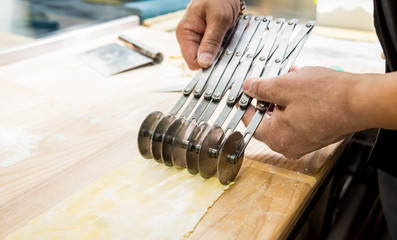 Chef rolling dough with a pasta machine. Pasta maker machine. 