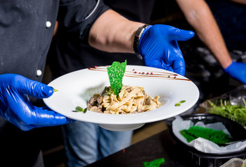 Chef cooking pasta with meat in pan. Italian style cuisine. Restaurant.