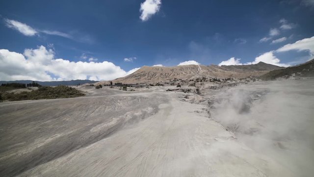 Wind blowing plenty of sand through the Sea of Sand in Bromo Tengger National Park, East Java, Indonesia. Active volcano Mount Bromo in the background.