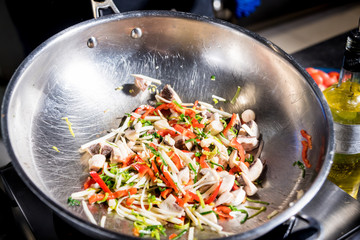 Chef cooking pasta with vegetables in pan. Italian style cuisine. Restaurant.
