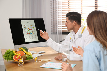 Nutritionist consulting patient at table in clinic