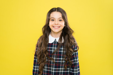 Hair like fire. back to school. small girl classy checkered dress. kid fashion concept. care about her hair. child has long curly hair. after visit to hairdresser. happy schoolgirl in stylish uniform