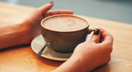 Close up of female hands holding coffee mug