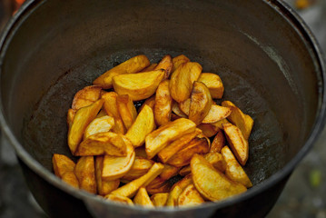 Potatoes are cooked in a large pot on fire. Food is cooked on a campfire in marching conditions.