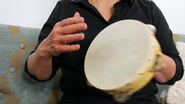 Forward facing view of a woman playing a tambourine, static handheld