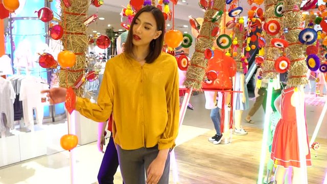 Asian woman with a beautiful smile in a department store looking at home decorations in a Chinese style