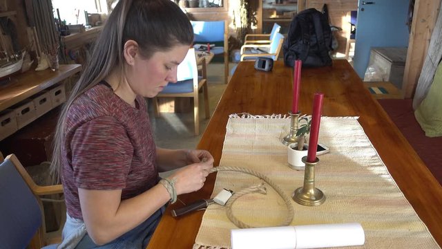 Young woman splicing a loop of rope for a boat.