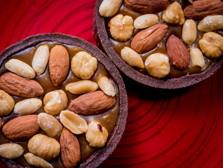 Chocolate cookies with almond nuts on a red plate. Restaurant.