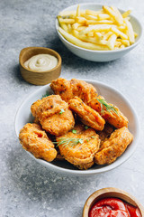 Fried crispy chicken nuggets with french fries and ketchup on light gray background. Seletive focus