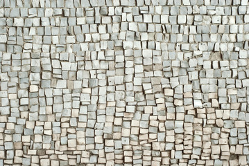 Texture of a wall made of small stones. The wall is covered with white granite cubes.