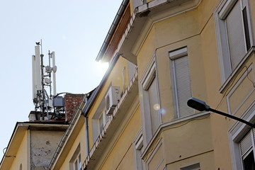 Fototapeta na wymiar Bird landed on a High Tech Telecommunication Antenna Tower mounted on a building