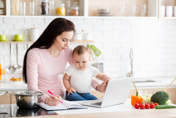 Busy woman trying to note down project with fidgety toddler