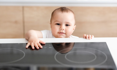 Alone curious baby touching hot electric cooktop