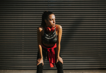 Pretty young woman takes a break after running in urban area