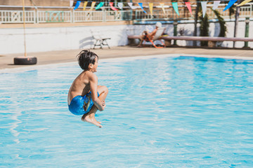 Naklejka premium young asina boy jumping into the swimming pool