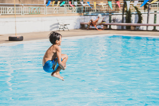 young asina boy jumping into the swimming pool