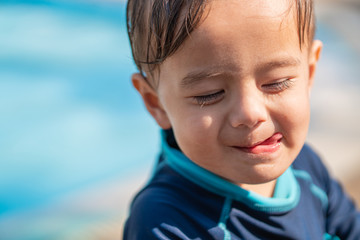 cute young mixed race boy smiling in the sun and licking his lips