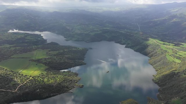 Beautiful scenic aerial view of the Evretou Dam reservoir in Cyprus with clouds reflecting in the water and lush green hills surrounding the lake.