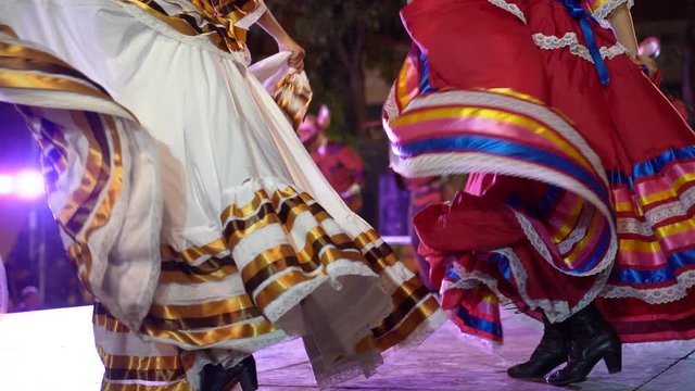 Slow motion closeup of flowing Mexican folk dance dresses on stage.