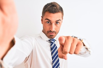 Young handsome business man taking selfie using smartphone over isolated background pointing with finger to the camera and to you, hand sign, positive and confident gesture from the front