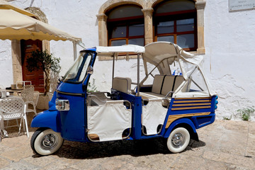 Fototapeta na wymiar Tuk-tuk, small car used mainly for tourists, standing in the street of Ostuni town, Apulia region, Italy, Adriatic Sea