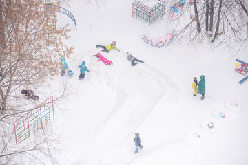 Children playing on a snow slide in kindergarten on winter day