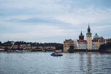 Obraz premium Beautiful architecture of Prague on a calm sunny day over the waters of Vltava river. One of the most popular European travel destinations. Admiring a romantic sunset from a boat.