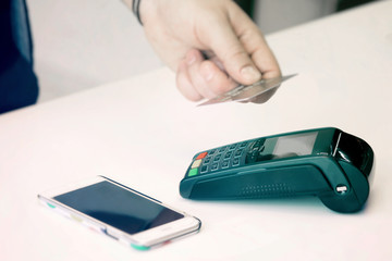 Fototapeta premium Credit card payment. Contactless card payment. A man pays for a purchase in a store with a credit card.