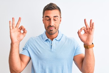 Young handsome elegant man wearing blue t-shirt over isolated background relax and smiling with eyes closed doing meditation gesture with fingers. Yoga concept.