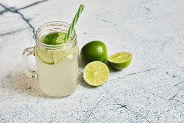 Lemonade with lemons on a light concrete background. Summer refreshing drink..Lemonade in a glass jar with mint and lemons.