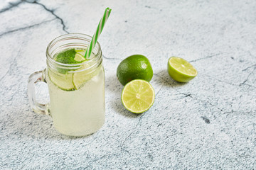 Lemonade with lemons on a light concrete background. Summer refreshing drink..Lemonade in a glass jar with mint and lemons.