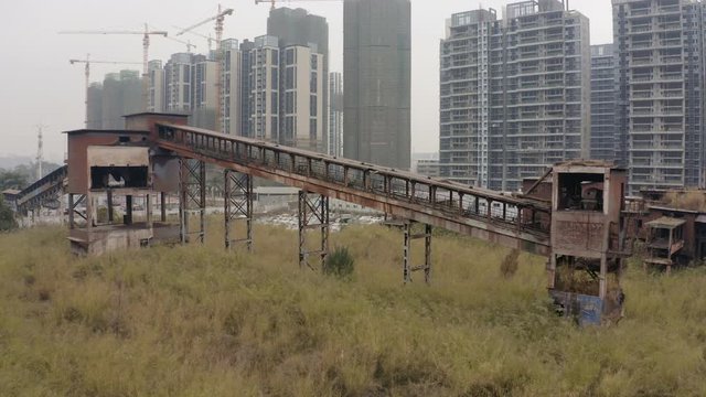 Abandoned steel factory mill with conveyor in between living apartment blocks, Guangzhou, China, Aerial shot.