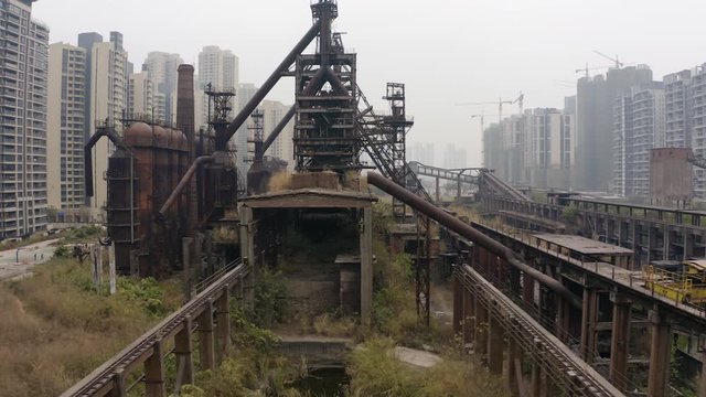 Abandoned steel factory mill with conveyor in between living apartment blocks, Guangzhou, China, Aerial shot.