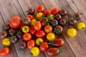 Different colors and shapes of fresh tomatoes on a wooden table. Vegan vegetarian diet. Garden.