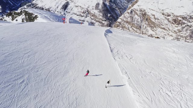 Aerial Following Shot of Professional Skier and Snowboarder going Down the Snowy Slope.
Drone Following Skiers Downhill.
