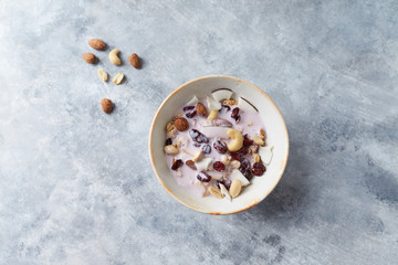 Bowl of granola with yogurt, nuts, cranberry and cocoanut. Concept for a tasty and healthy meal. Stone  background. Top view. Copy space. 